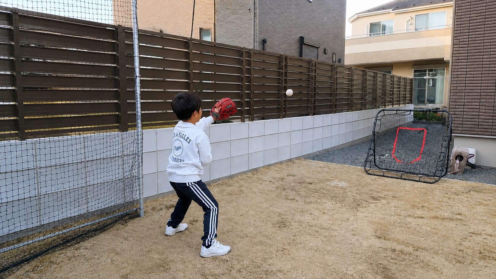 自宅の庭で返球ネットを使ってひとりキャッチ練習をする少年野球の子ども