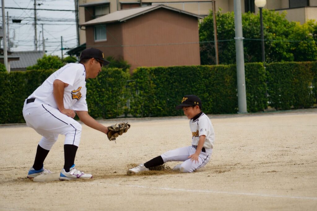 少年野球の練習中に親子でスライディング練習をしている様子